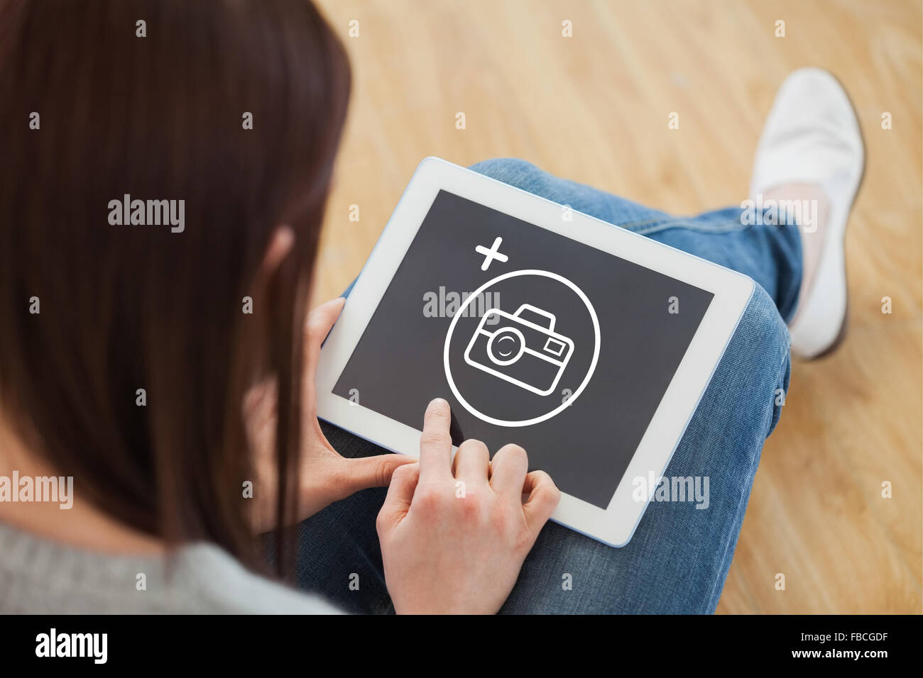 Composite image of girl using a tablet pc sitting on the floor Stock Photo