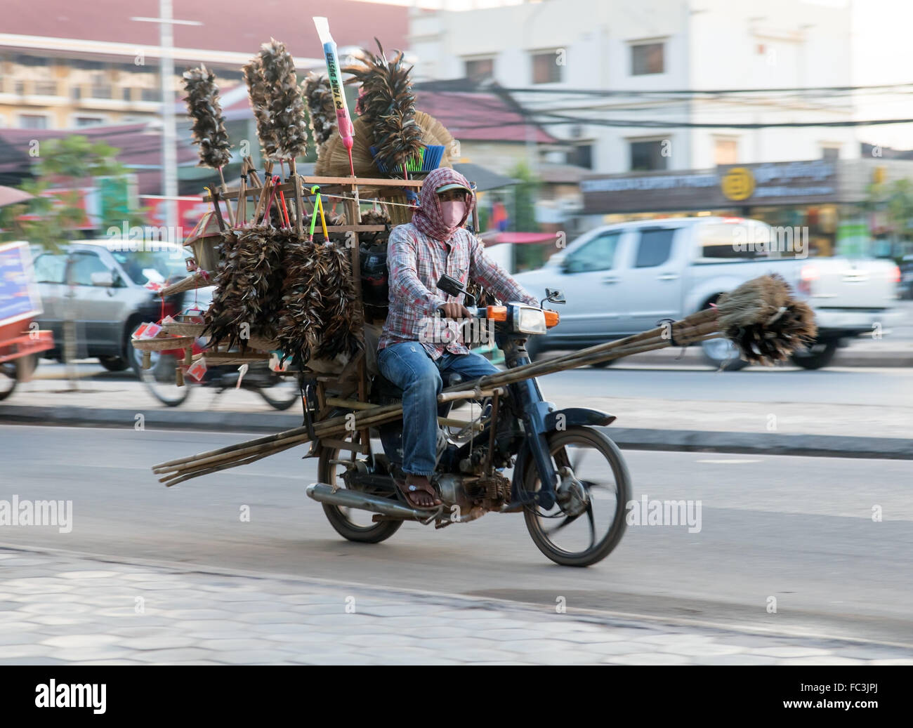 man on a motorcycle carrying brooms Stock Photo