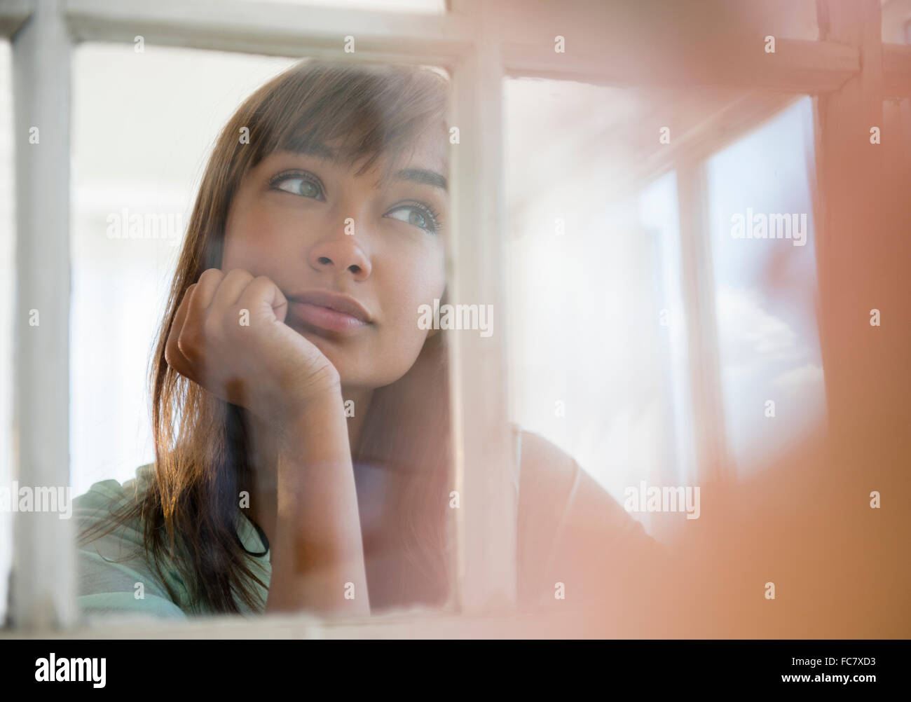 Mixed race woman looking out window Stock Photo