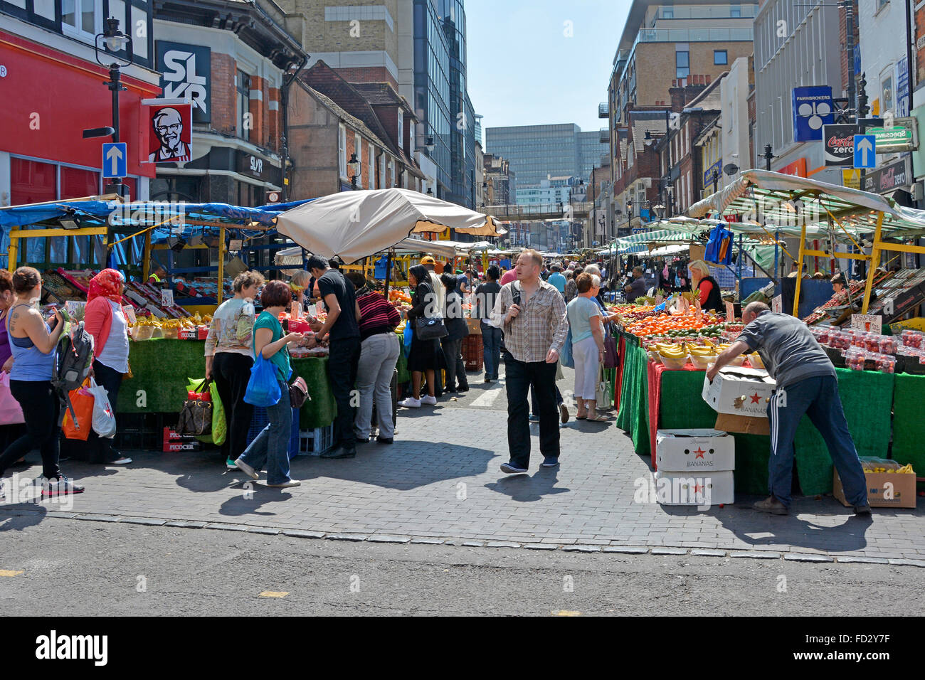 Summer shoppers and stallholder at retail fruit and vegetables stalls in busy Surrey Street market Croydon South London England UK Stock Photo