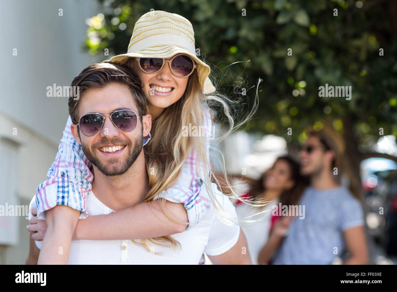 Hip man giving piggy back to his girlfriend Stock Photo