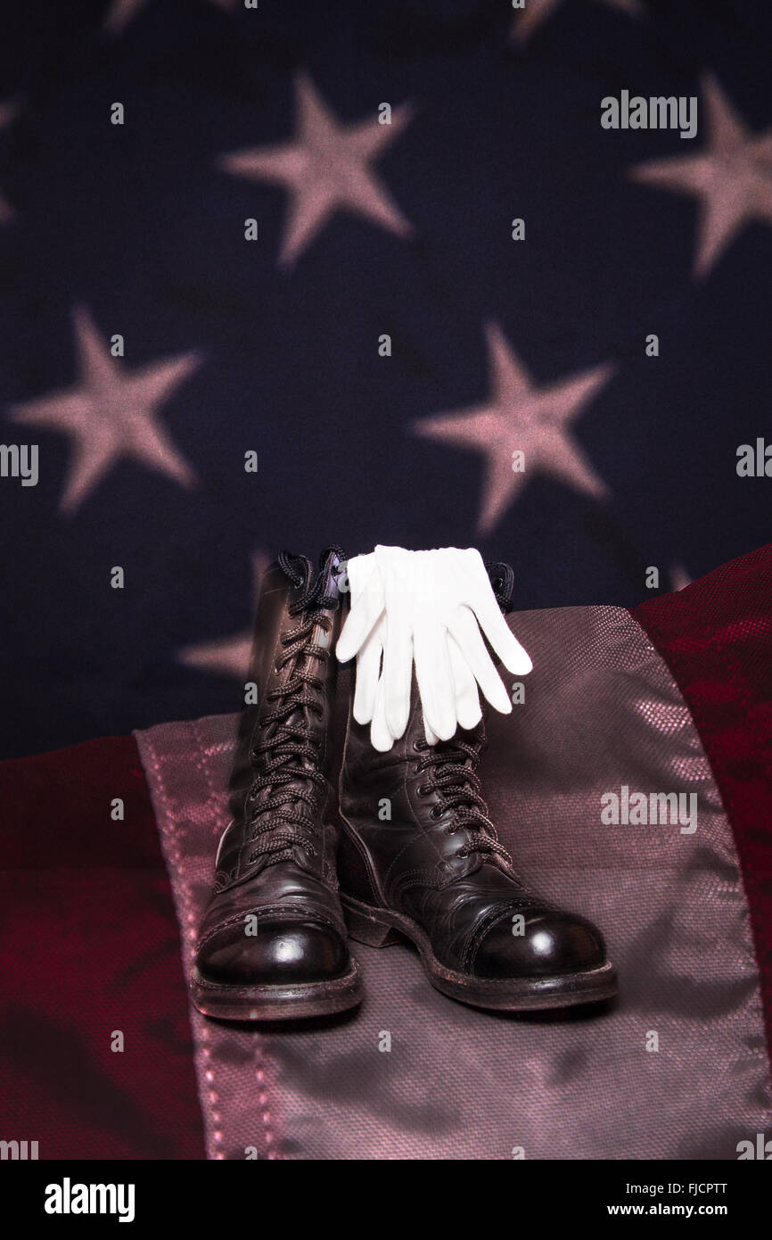 A pair of combat boots and white dress gloves on an American Flag background. Stock Photo