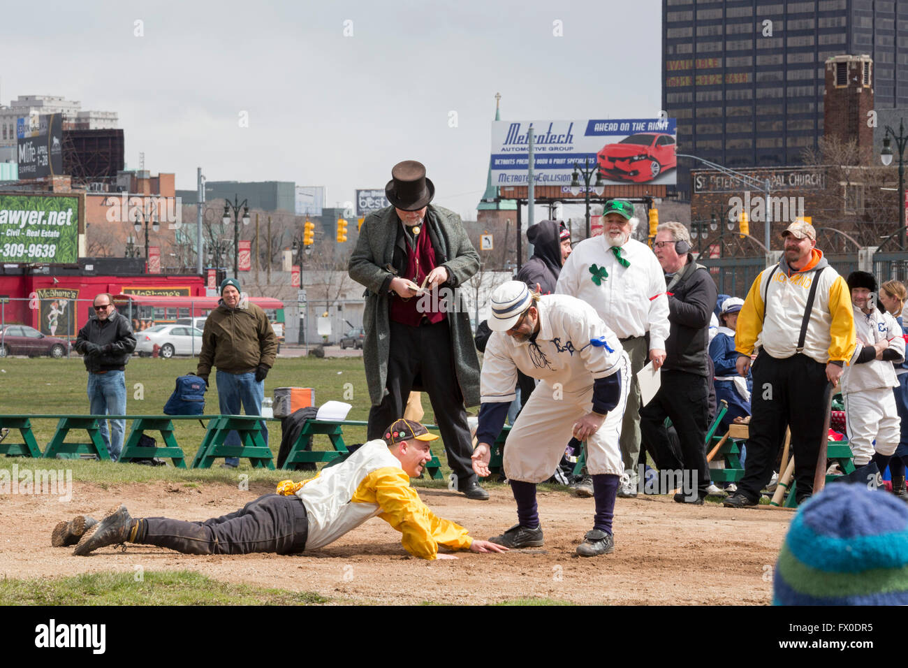 Detroit, Michigan USA - 9 April 2016 - A vintage base ball game, with rules and uniforms from the 1860s, is played to say farewell to Navin Field. As Navin Field and later Tiger Stadium, the field was home to the Detroit Tigers from 1912-1999. Since then, the field has been maintained by volunteers; it will now be redeveloped as a retail and residential complex with a playing field for youth sports. After sliding into home, a player gets a hand from the opposing catcher. Credit:  Jim West/Alamy Live News Stock Photo