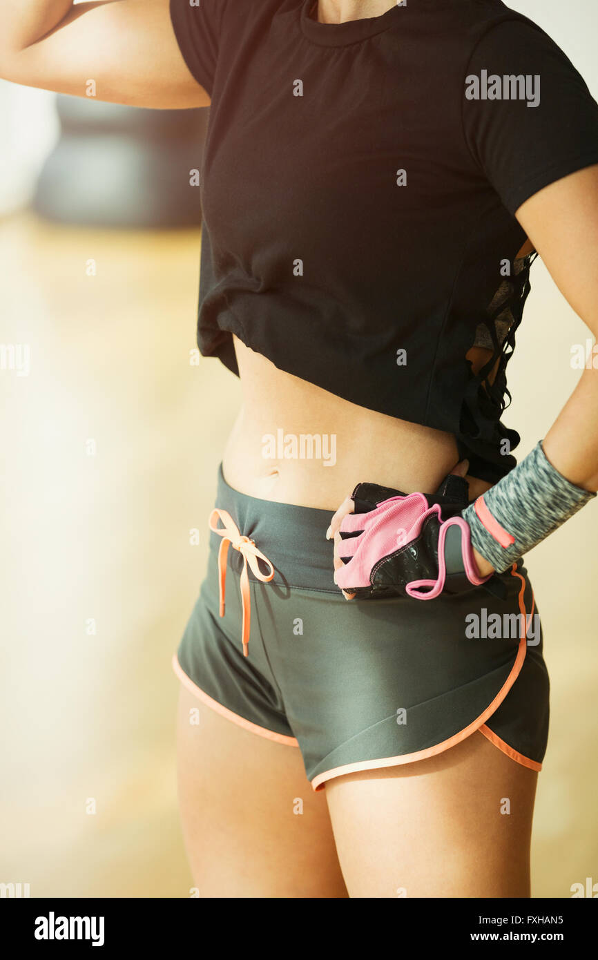 Midsection fit woman wearing short running shorts at gym Stock Photo