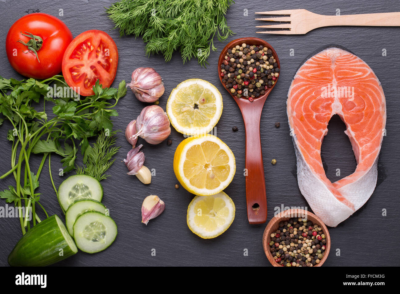 red fish steak with spices and vegetables on a slate table. Stock Photo