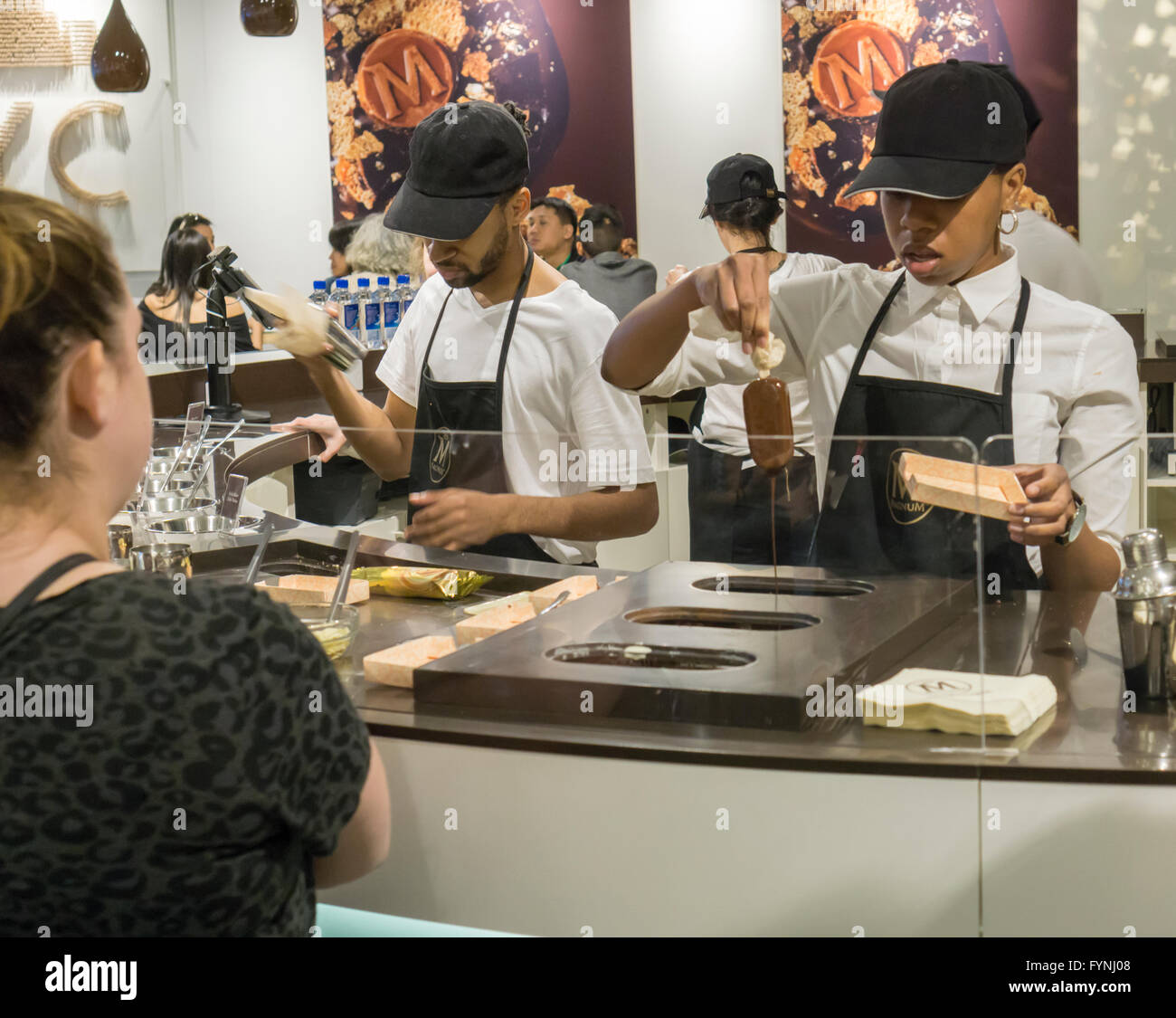 Customers line up for their bespoke Magnum ice cream bar studded with toppings at the Magnum pop-up dipping bar in Soho in New York on Saturday, April 23, 2016. Workers for Magnum, a brand of the Good Humor company, dip your bar in up to three ingredients including everything from Himalayan sea salt to the more plebeian nuts. The pop-up is open through August 7. (© Richard B. Levine) Stock Photo