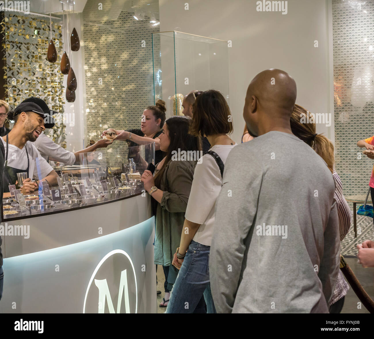 Customers line up for their bespoke Magnum ice cream bar studded with toppings at the Magnum pop-up dipping bar in Soho in New York on Saturday, April 23, 2016. Workers for Magnum, a brand of the Good Humor company, dip your bar in up to three ingredients including everything from Himalayan sea salt to the more plebeian nuts. The pop-up is open through August 7. (© Richard B. Levine) Stock Photo