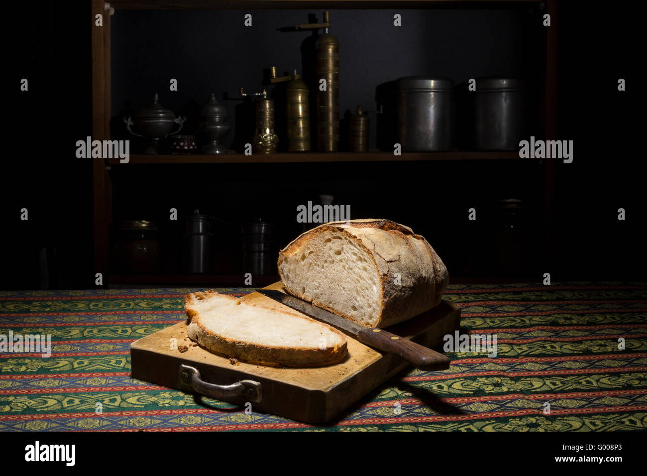 Loaf and slice of italian bread in a cutting board in a dark kitchen Stock Photo