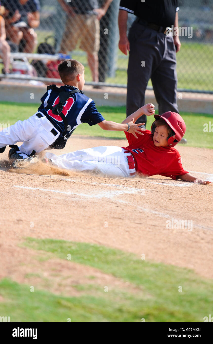 Little league player sliding home. Stock Photo