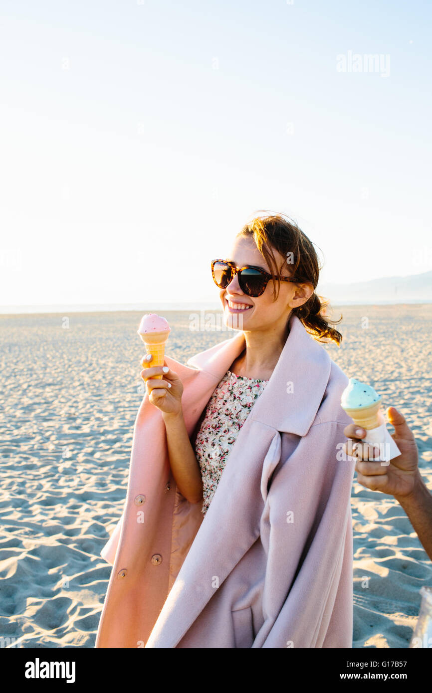 Stylish young woman with boyfriend eating ice cream cone strolling on beach, Venice Beach, California, USA Stock Photo