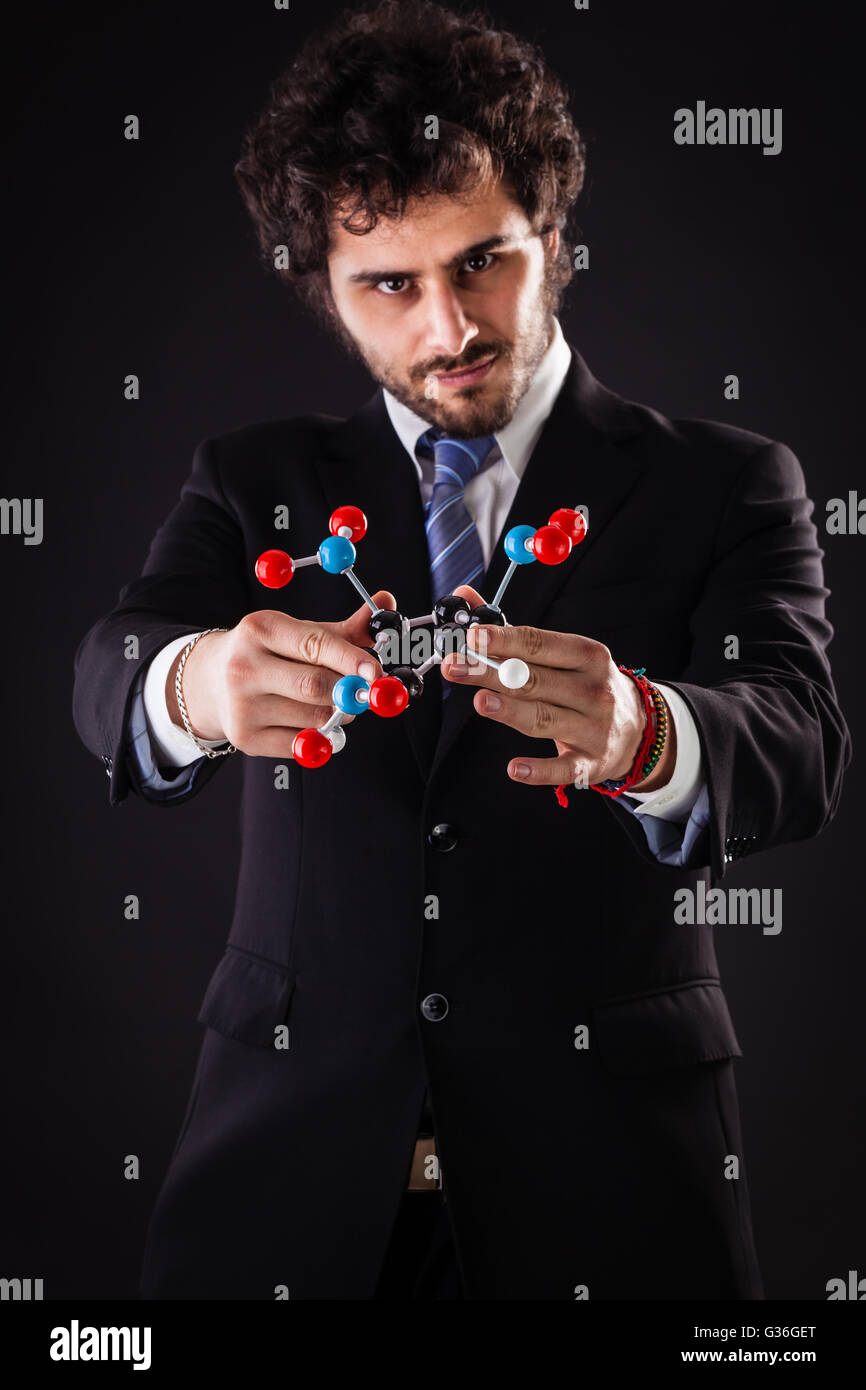 a businessman wearing a suit and a tie holding a trinitrotoluene tnt molecular model Stock Photo