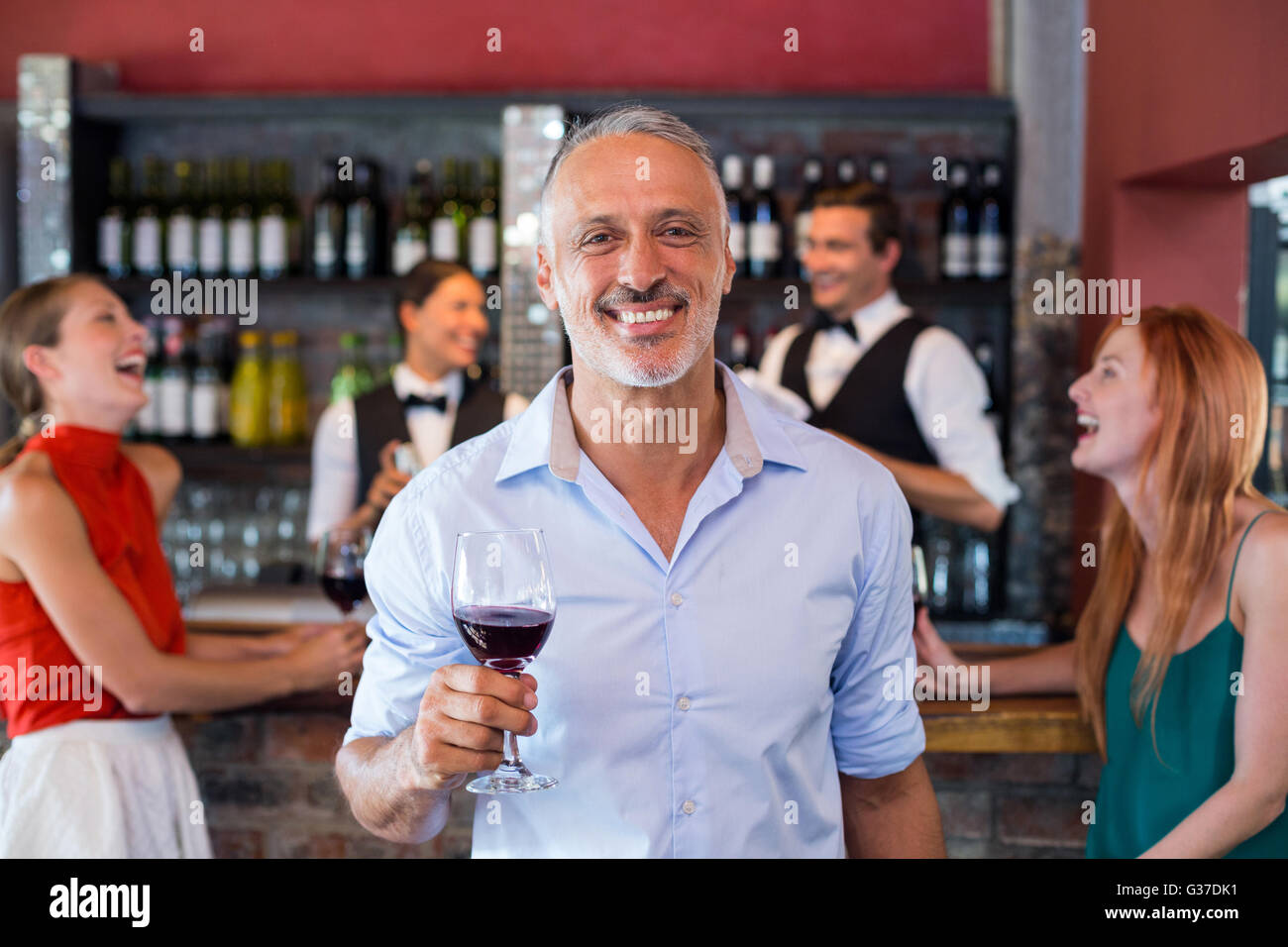 Portrait of man holding a wine glass in front of bar counter Stock Photo