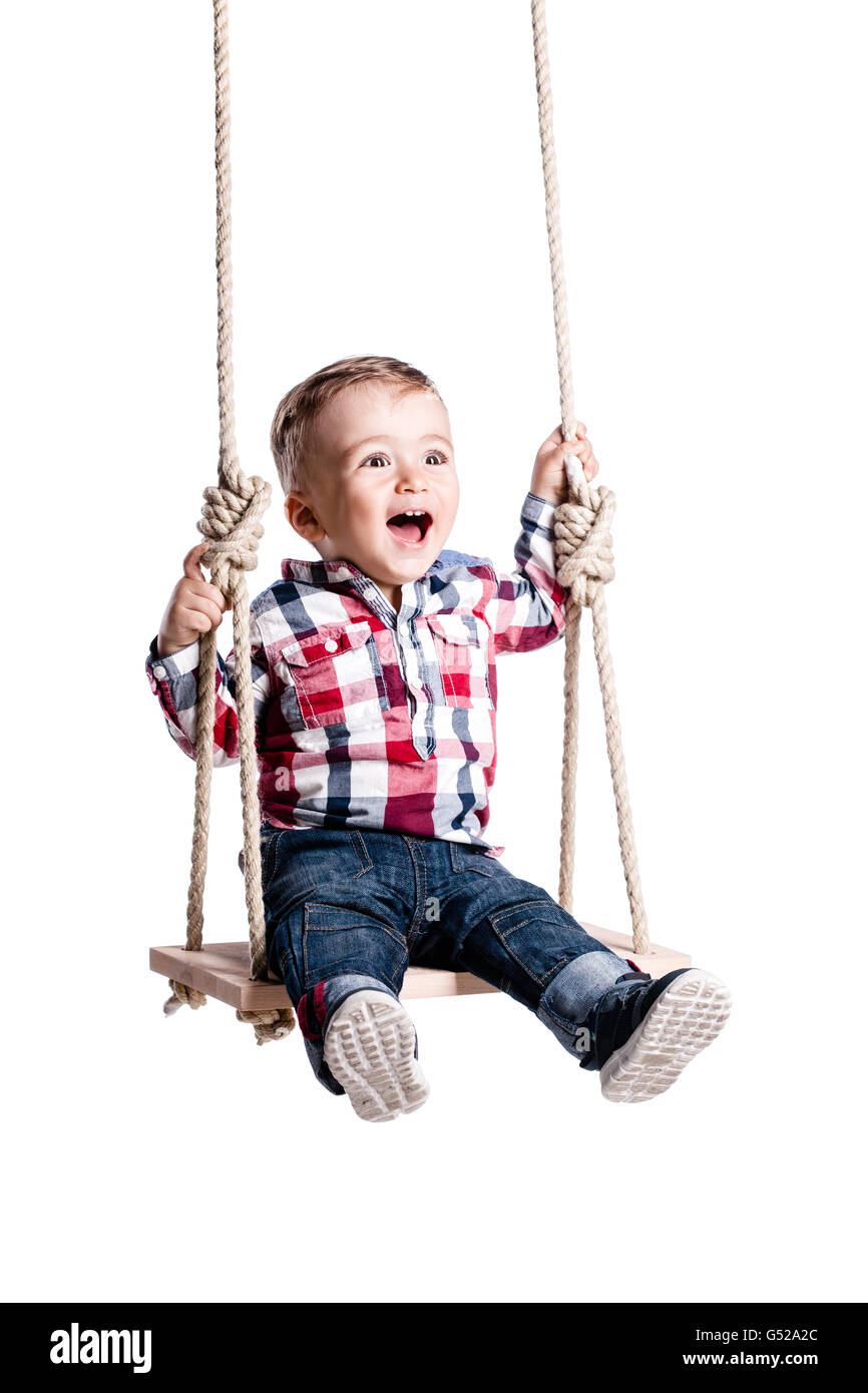 happy little boy swinging on a wooden swing Stock Photo