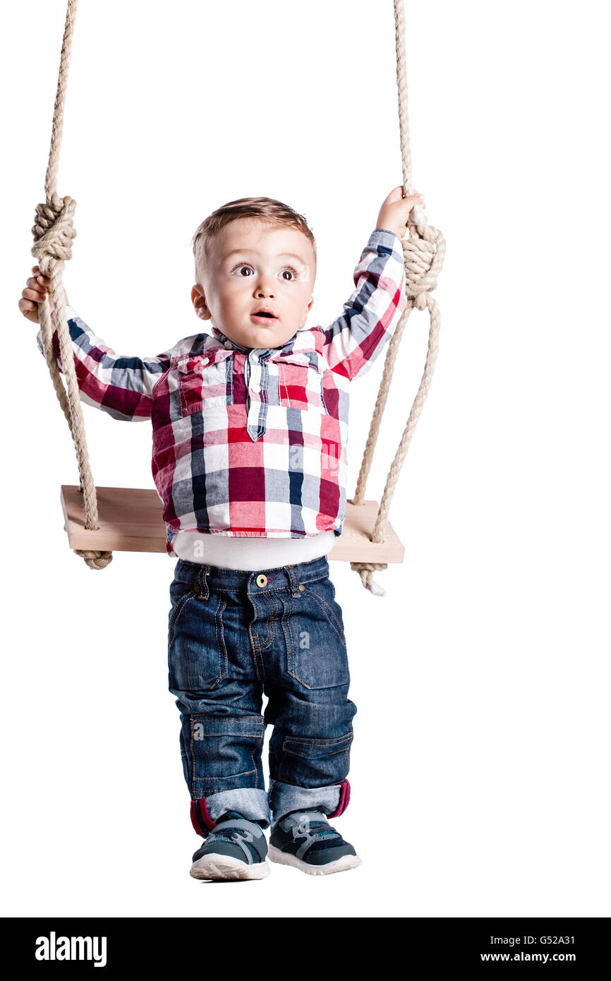 happy little boy swinging on a wooden swing Stock Photo