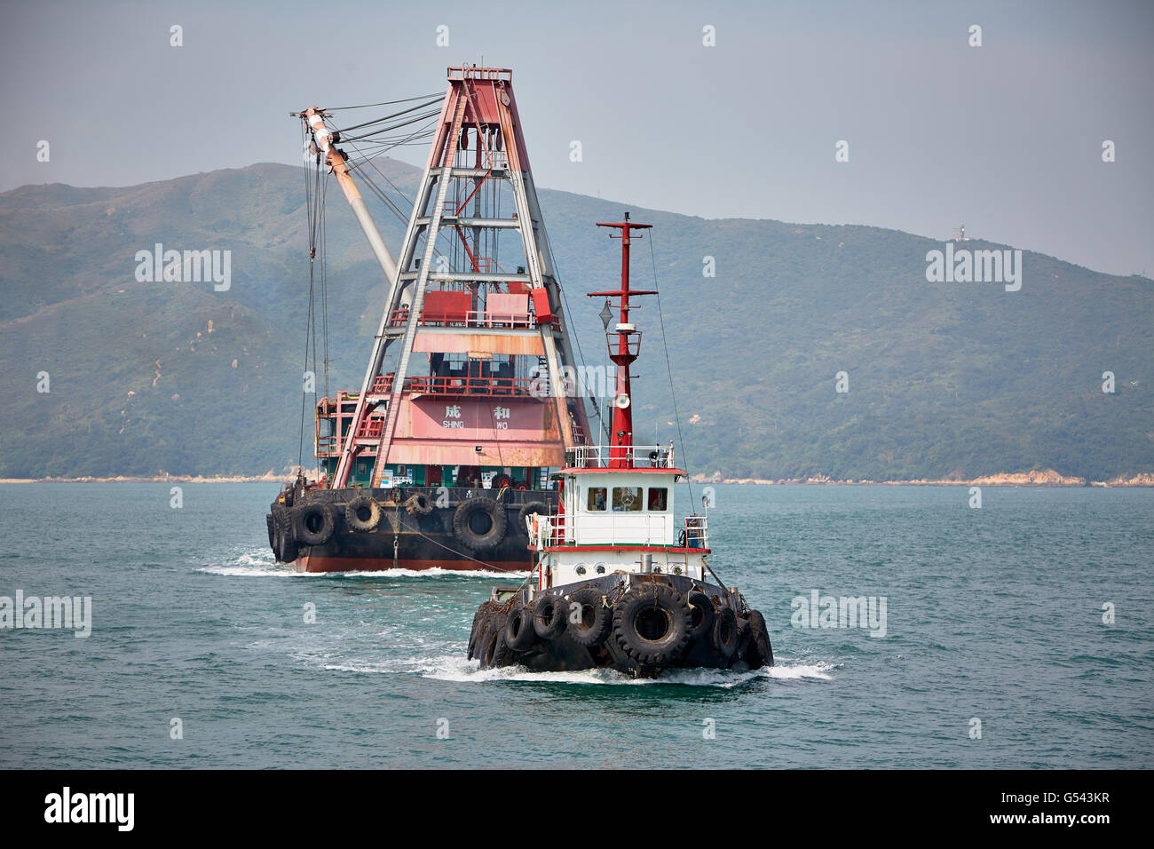 A tug towing a barge across the Rambler Channel in Hong Kong. Stock Photo