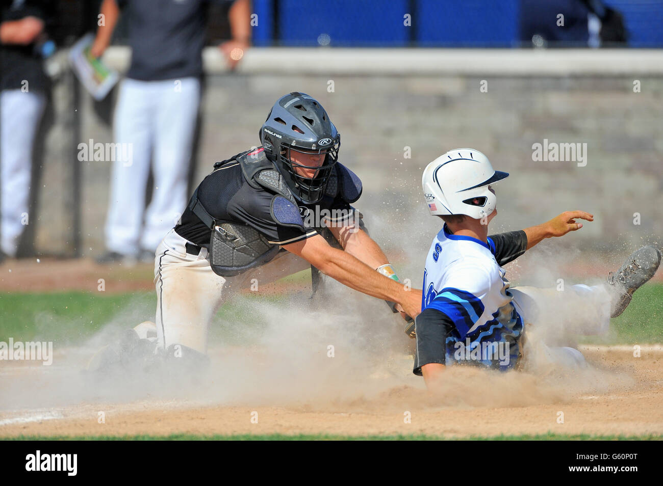 Catcher applying a tag to a sliding base runner who was caught trying to score on a ground ball to the infield. USA. Stock Photo