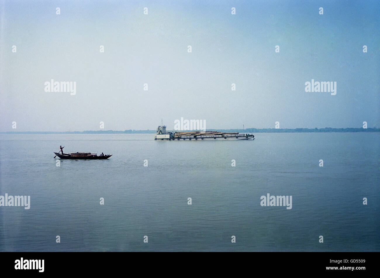 Timber-carrying barge and a country boat sailing Stock Photo