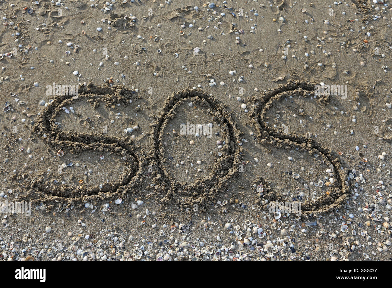 SOS big written on the beach sand Stock Photo