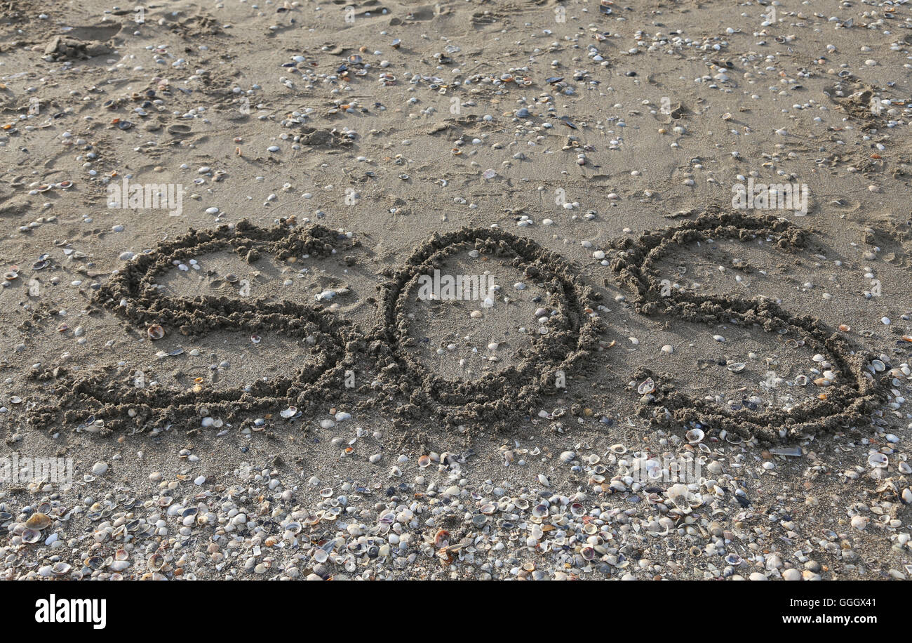 SOS big written on the beach by the sea Stock Photo