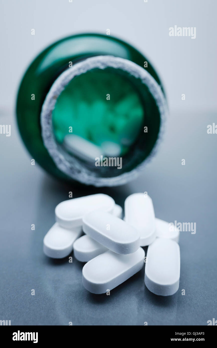 Oval pills by green pill bottle Stock Photo