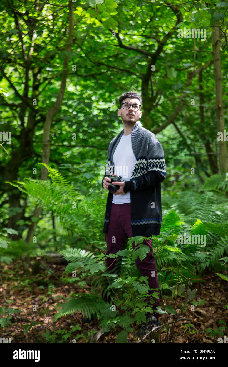 Portrait of man taking landscape photos with a DSLR in a forest. Caucasian Photographer shooting outside with digital camera. Stock Photo