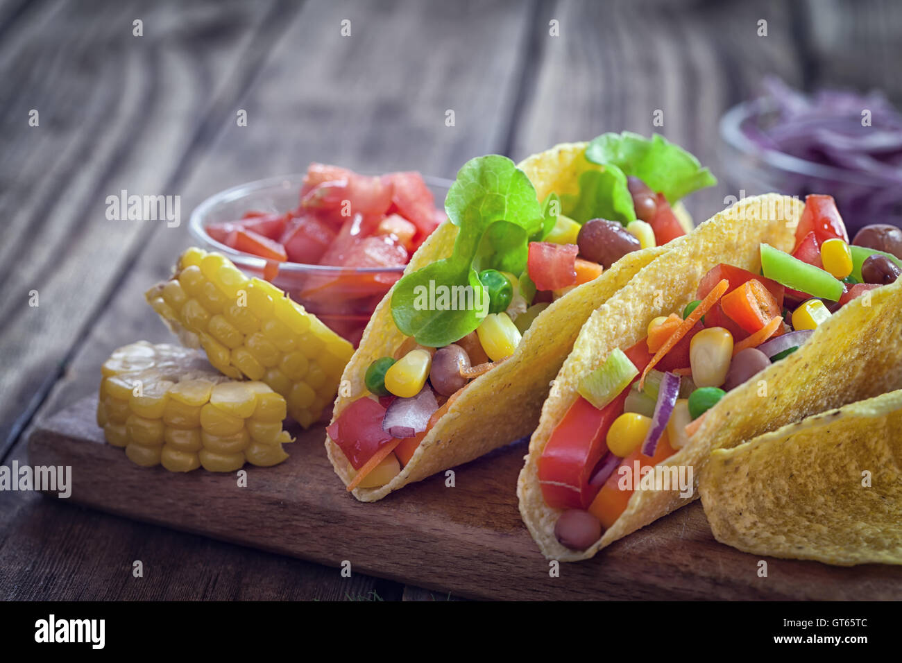 Mexican corn tortilla tacos with vegetables and grilled chicken on wooden background Stock Photo