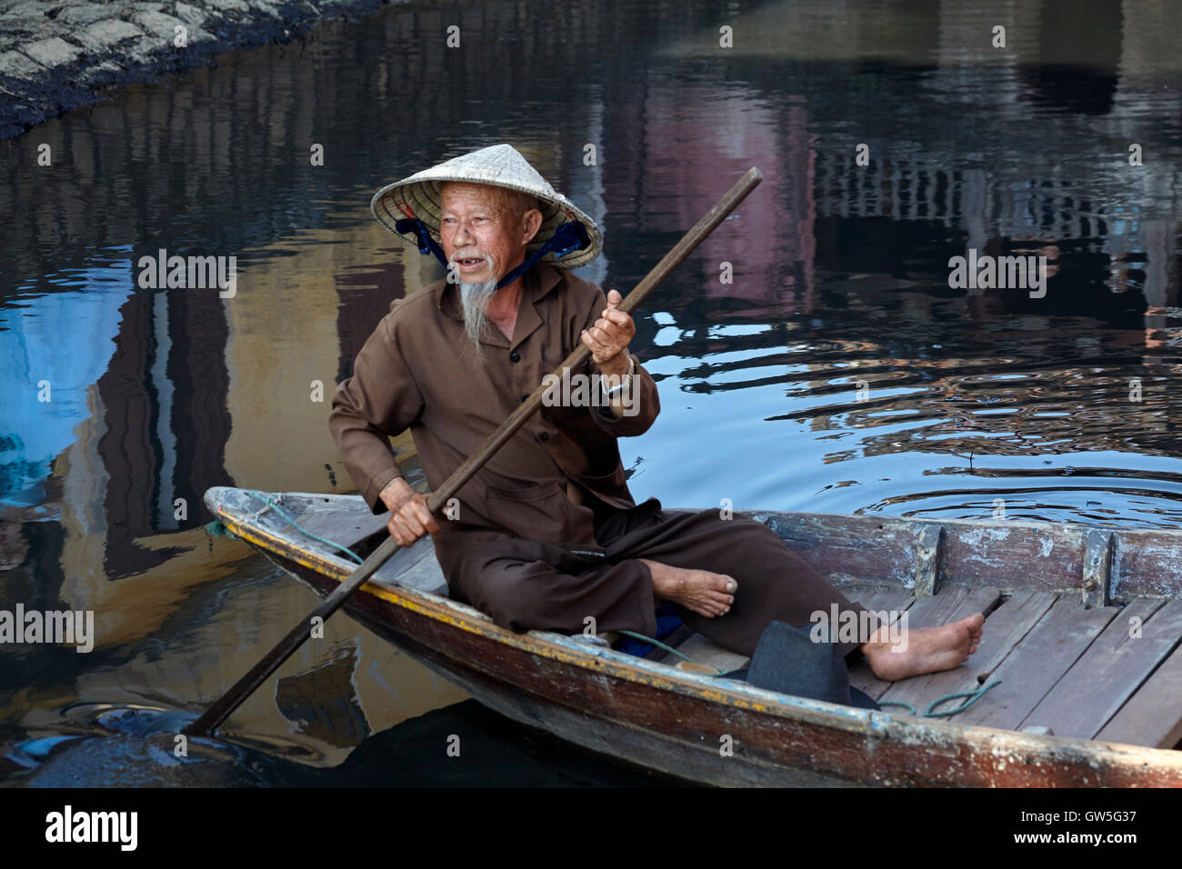 Elderly man with goatee and conical hat in boat, Hoi An (UNESCO World Heritage Site), Vietnam Stock Photo