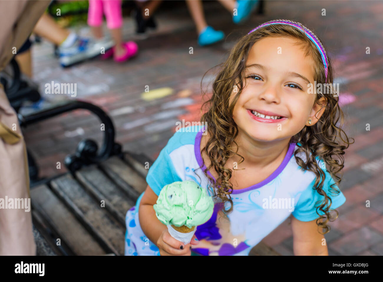 Portrait of cute girl eating ice cream cone on sidewalk Stock Photo