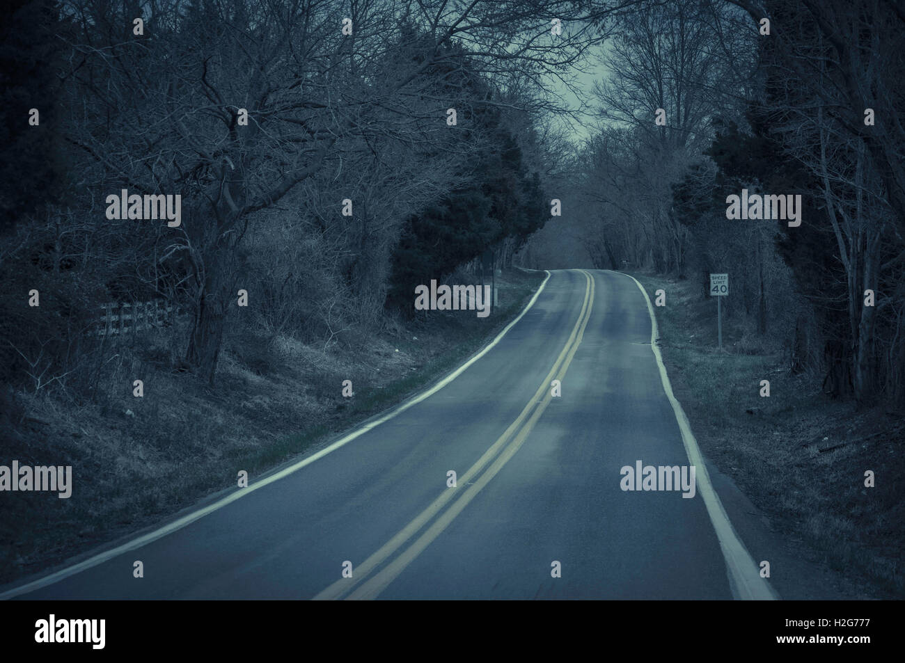 A dark eery creepy two lane road in the middle of nowhere, deep within the dark woods of Virginia. Stock Photo