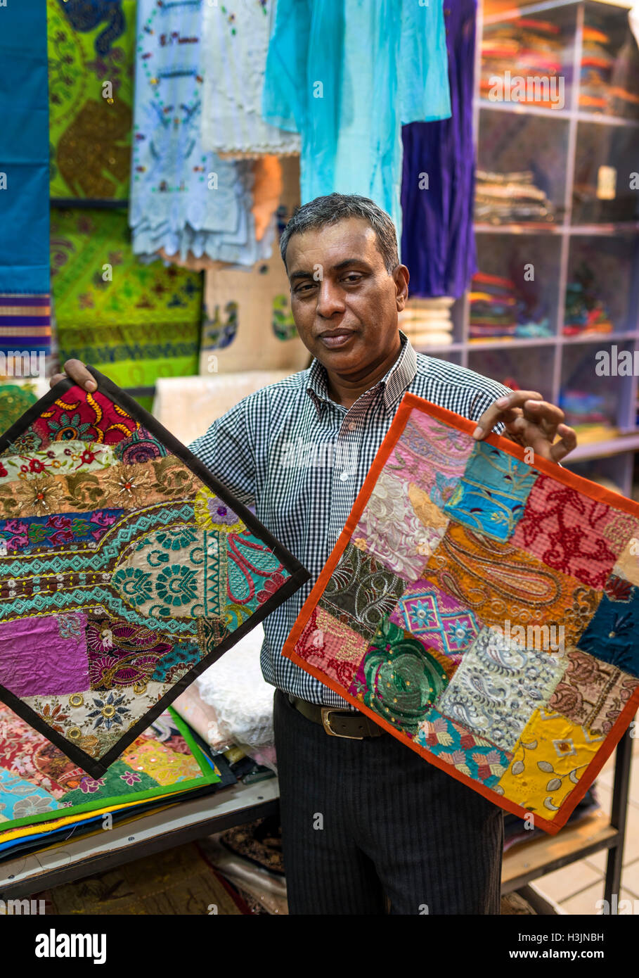 Man showing cushion covers for sale in Port Louis Market Stock Photo