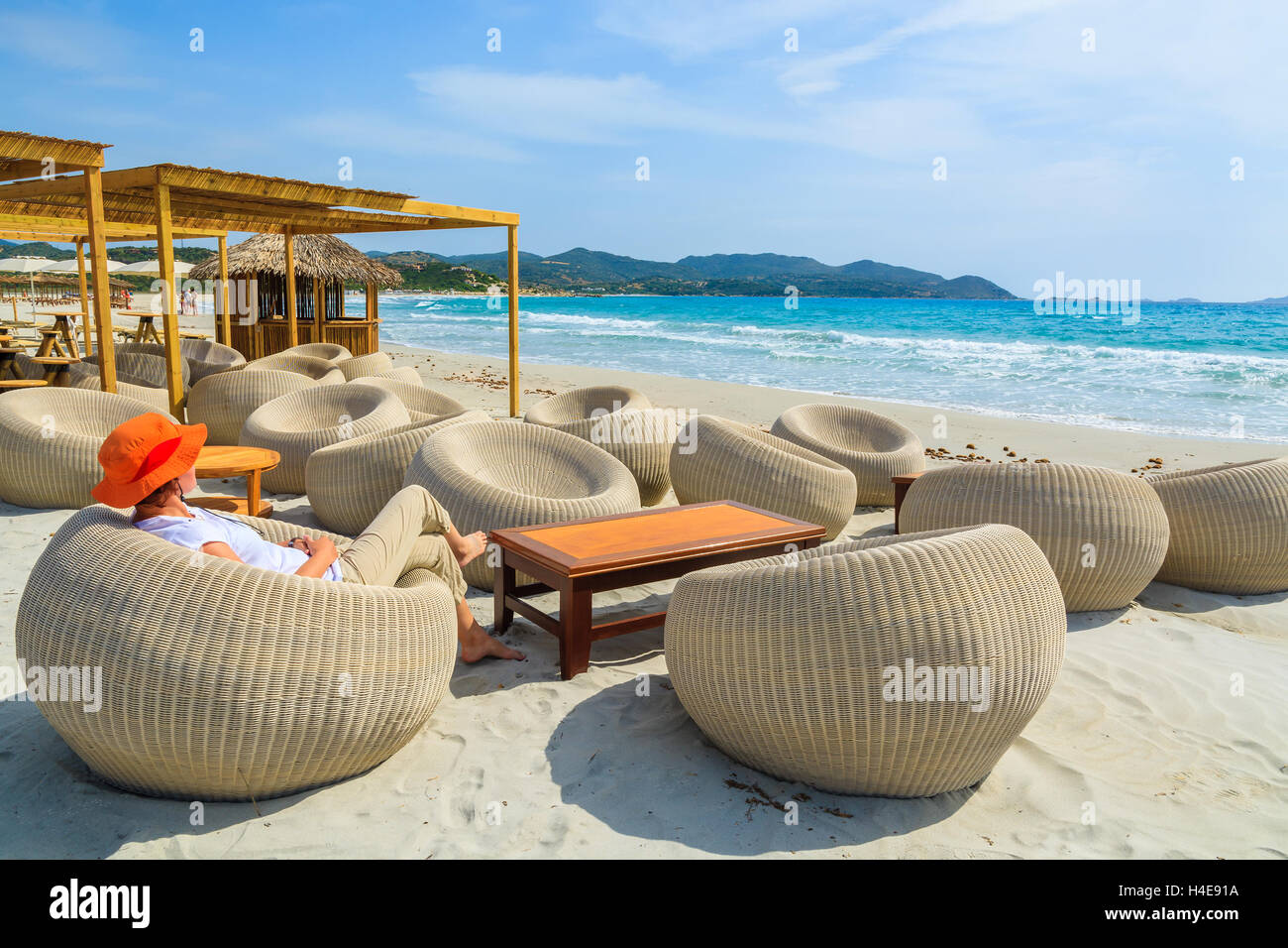 Young woman tourist sits in a beach bar at Porto Giunco bay, Sardinia island, Italy Stock Photo