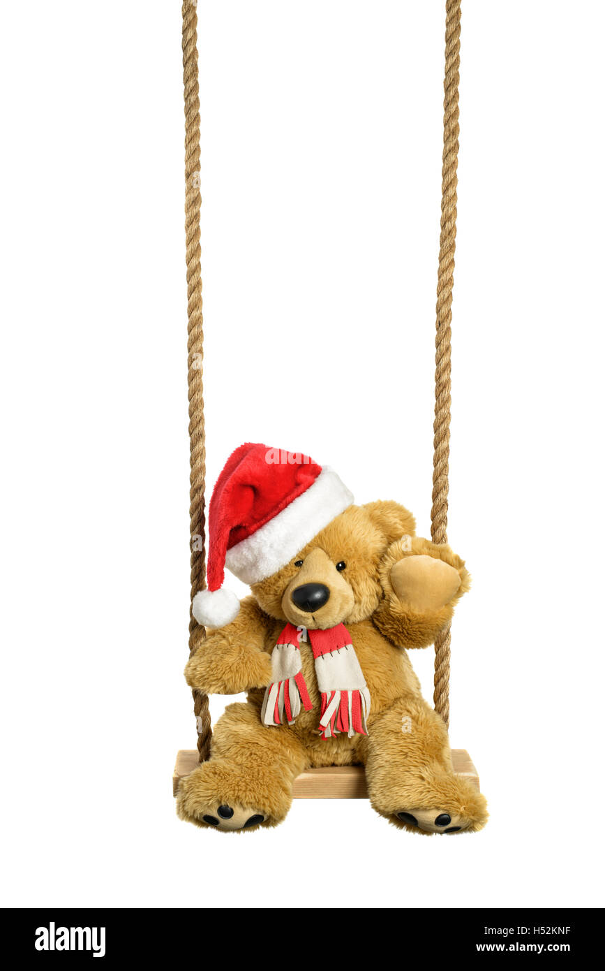 Teddy bear in santa hat on a wooden swing with white background Stock Photo