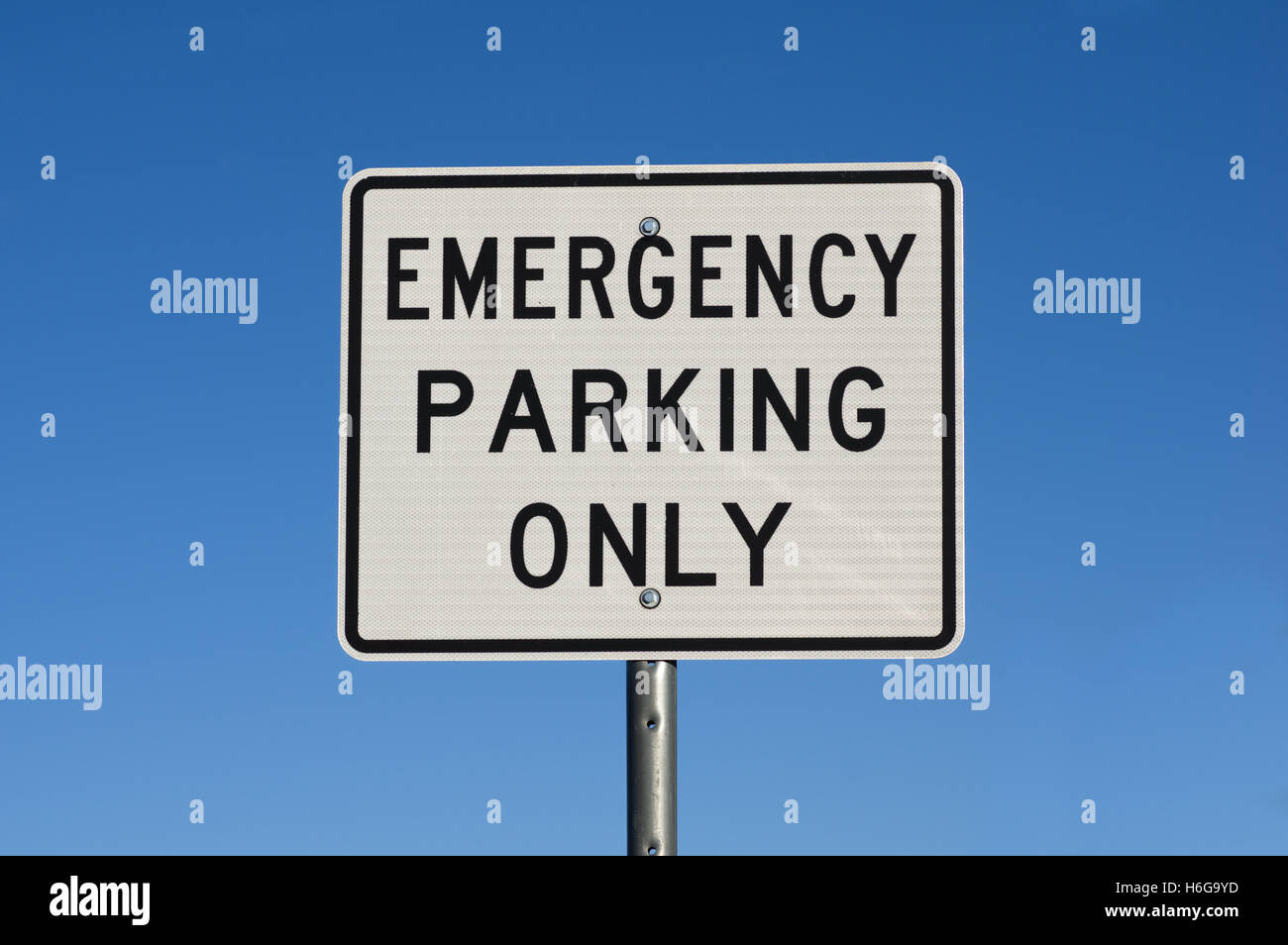 white and black emergency parking only road sign with blue sky background Stock Photo