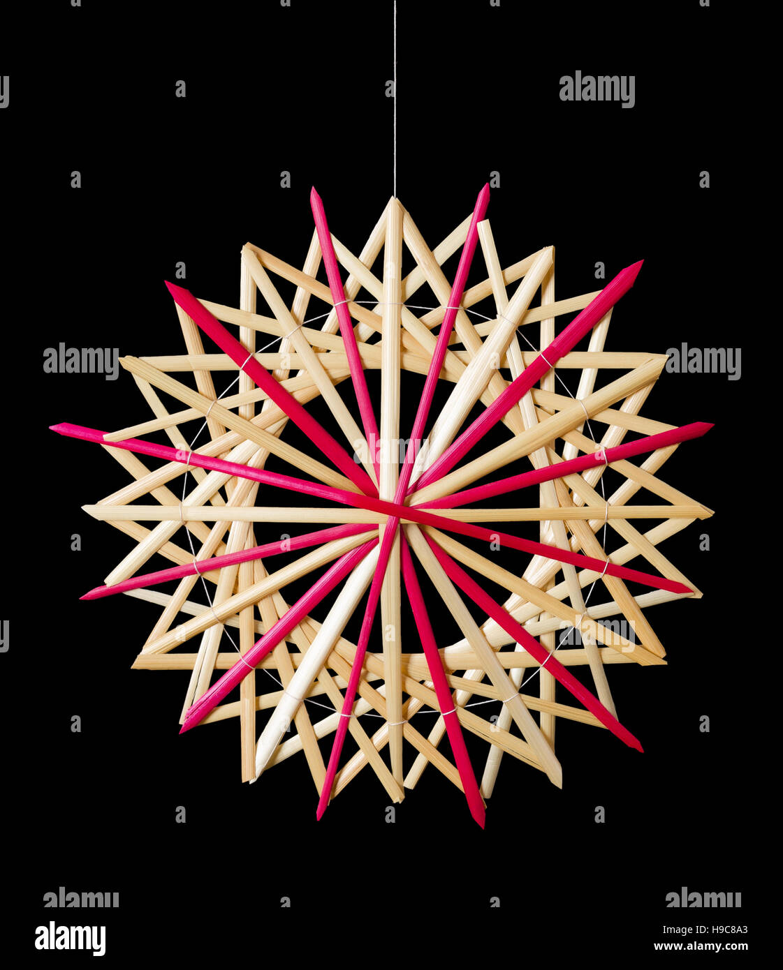 Straw star Christmas decoration on black background. Handmade colorful decor for windows, as gifts or to hang on the xmas tree. Stock Photo