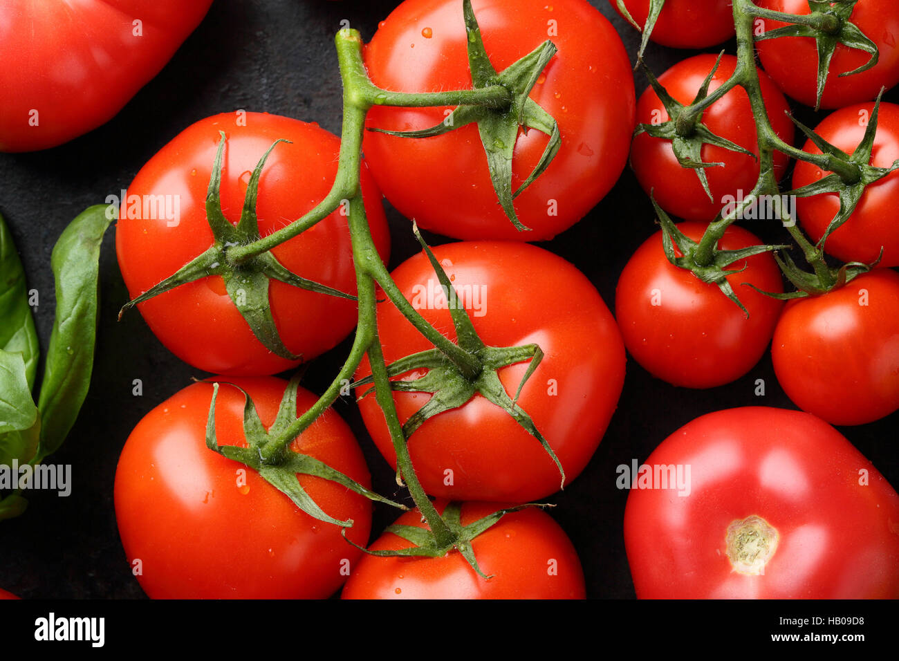 Branch of red tomatoes on black, food top view Stock Photo