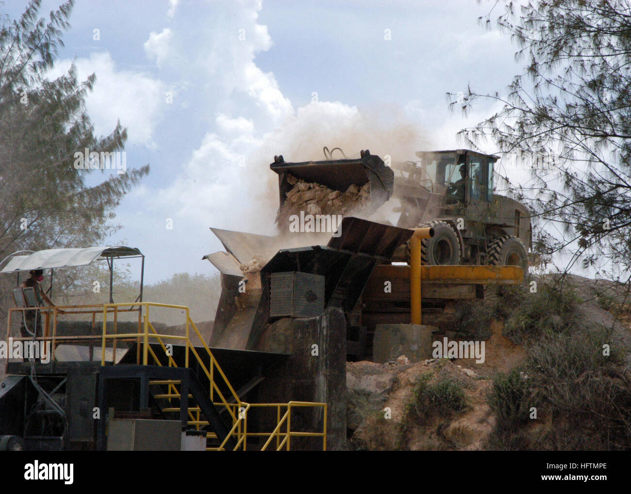 070424-F-8678B-044 CAMP COVINGTON, Guam (April 24, 2007) - Construction Electrician 3rd Class Jonathan Brace monitors the primary rock crusher while Constructionman Justin Dimmitt loads the hopper with a front-end loader. During normal quarry operations, Naval Mobile Construction Battalion (NMCB) 4 can produce an average of 60 tons of crushed rock per day. U.S. Air Force photo by Master Sgt. Rickie Bickle (RELEASED) US Navy 070424-F-8678B-044 Construction Electrician 3rd Class Jonathan Brace monitors the primary rock crusher while Constructionman Justin Dimmitt loads the hopper with a front-en Stock Photo