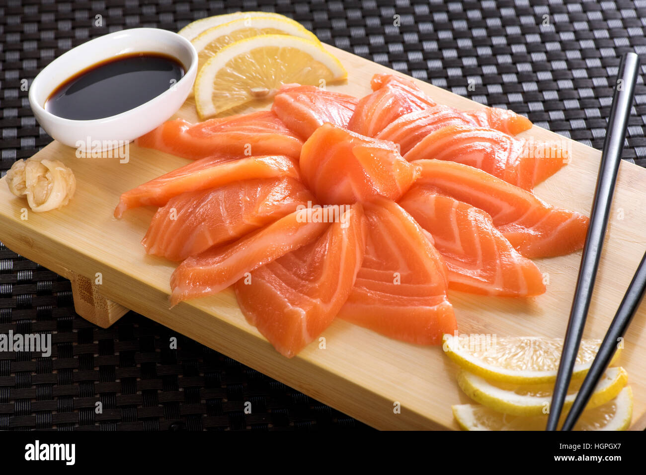 Sashimi salmon with lemon and soy sauce served on wooden board, Japanese cuisine Stock Photo