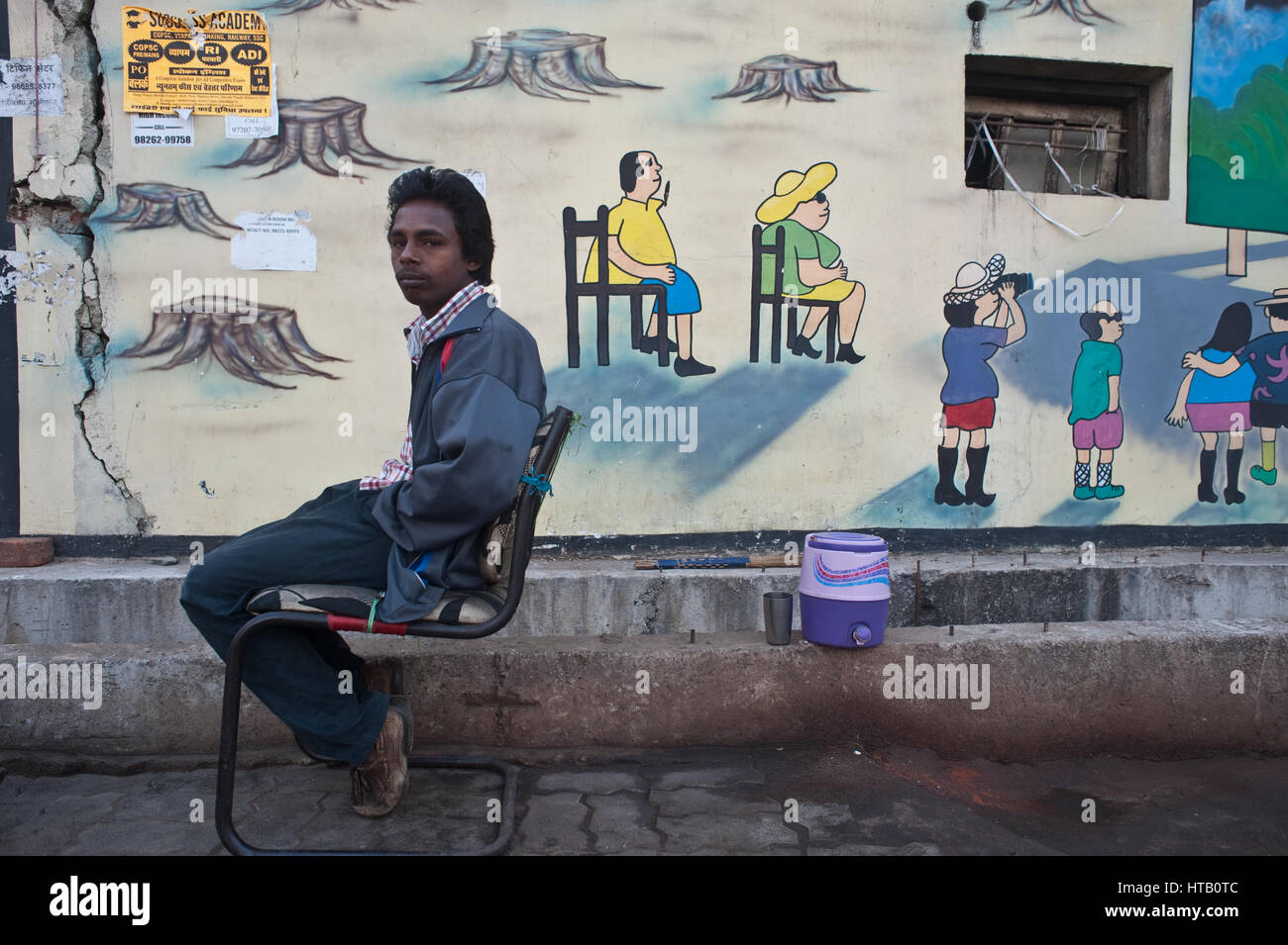 Boy selling coconuts in the street + mural painting representing tourists ( India) Stock Photo