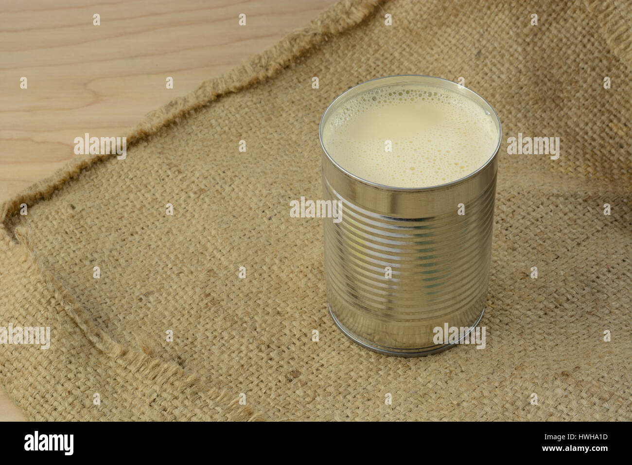 Canned evaporated milk in open can on burlap Stock Photo