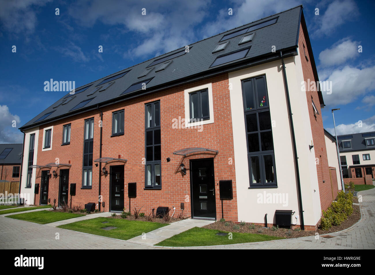 New red brick terraced houses all with solar black PV panels Persimmon Greenacres Bishops Cleeve Cheltenham UK Stock Photo