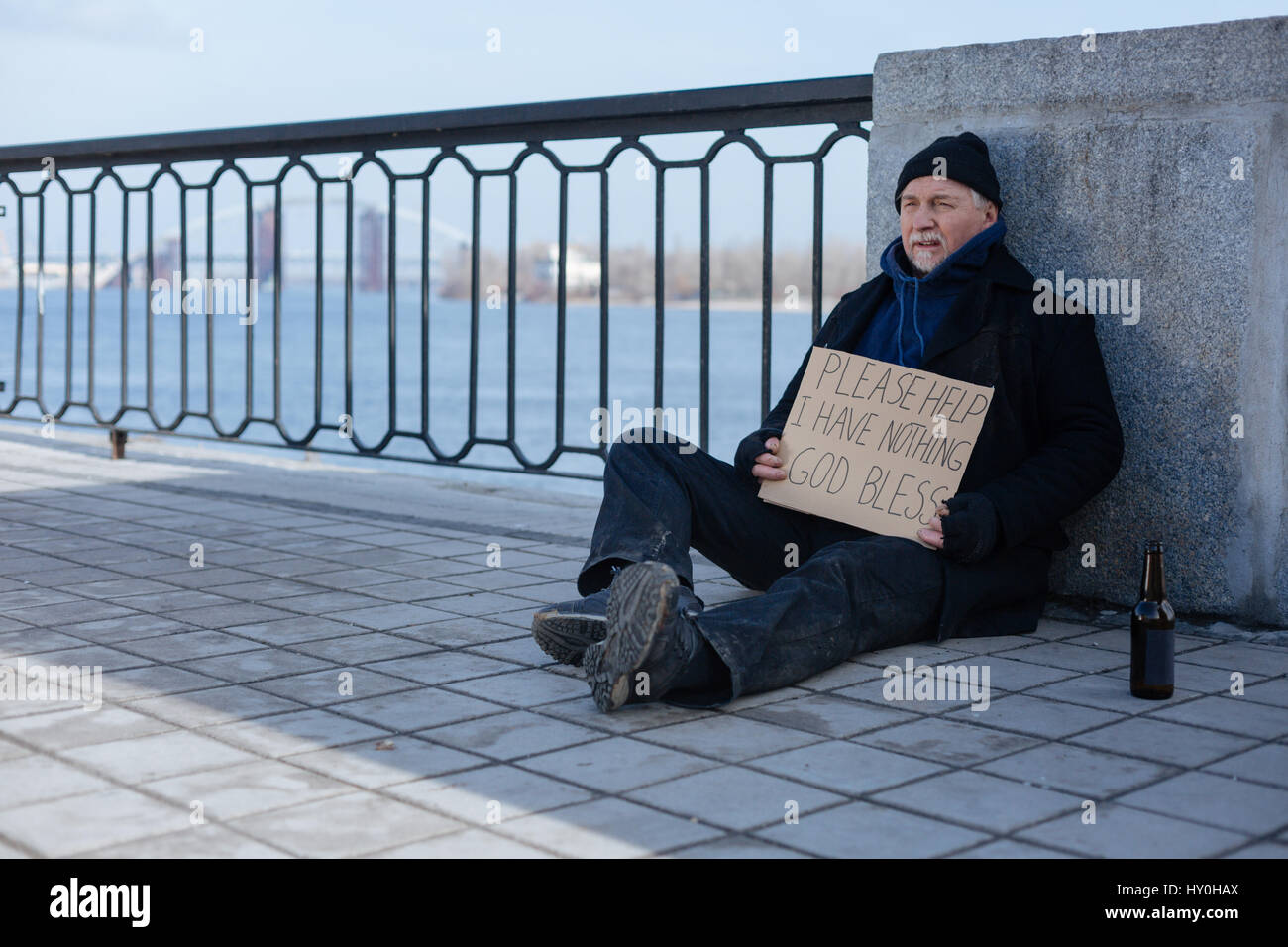 Poor man sitting near glass bottle Stock Photo