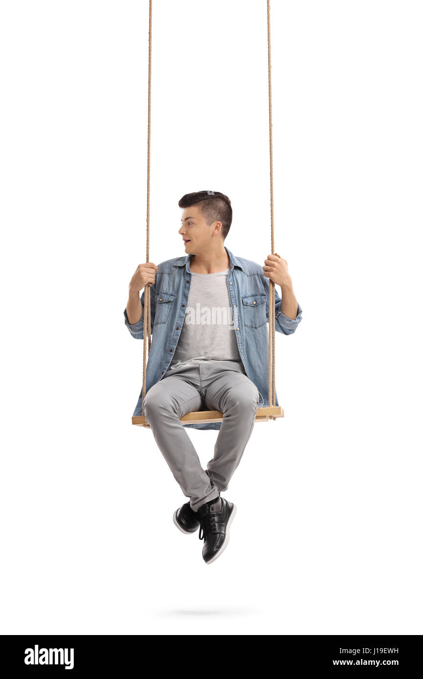 Teenager sitting on a swing and looking to the left isolated on white background Stock Photo