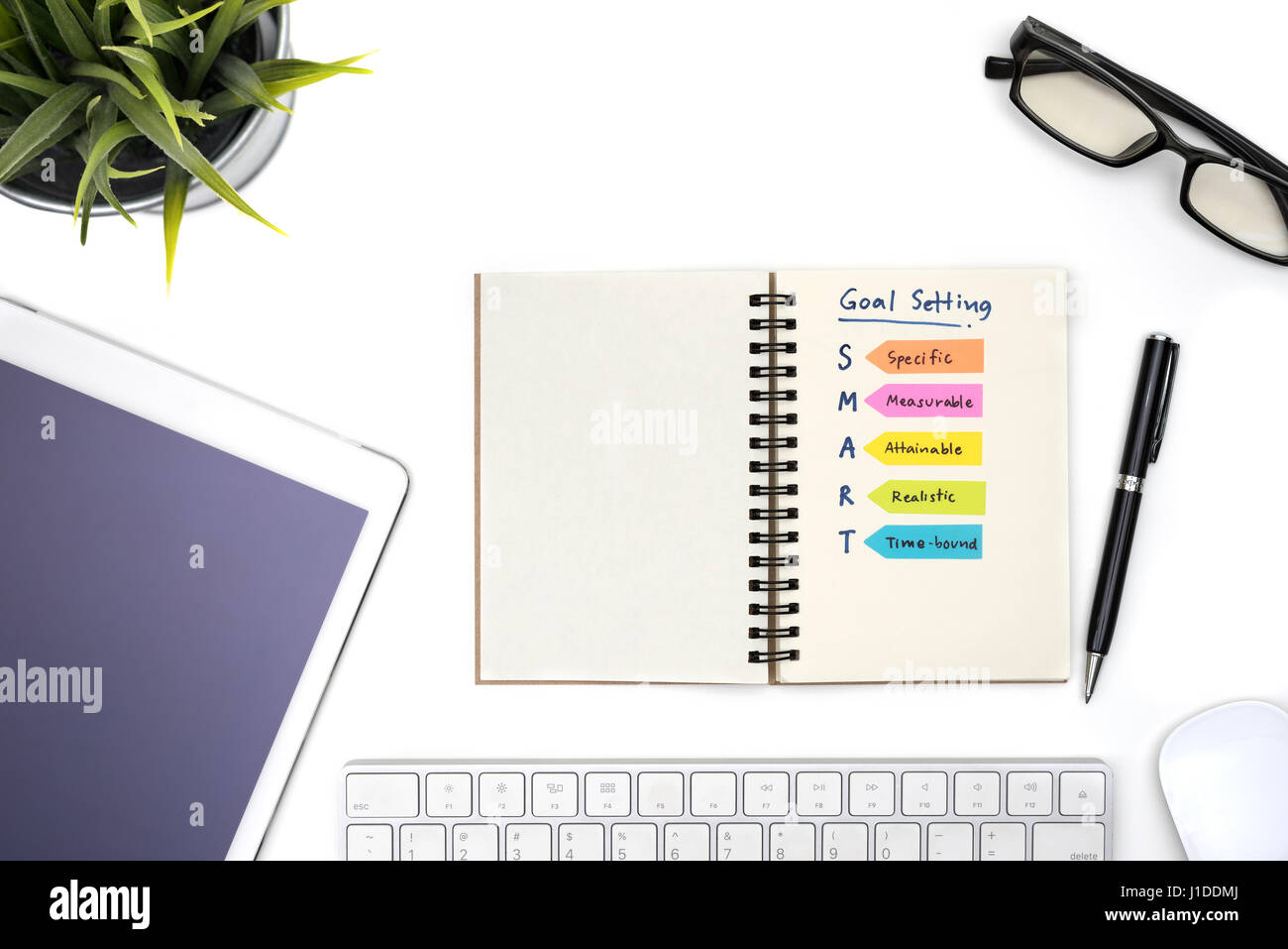 Smart goal setting with notebook, eye glasses, pen, mouse, keyboard ...