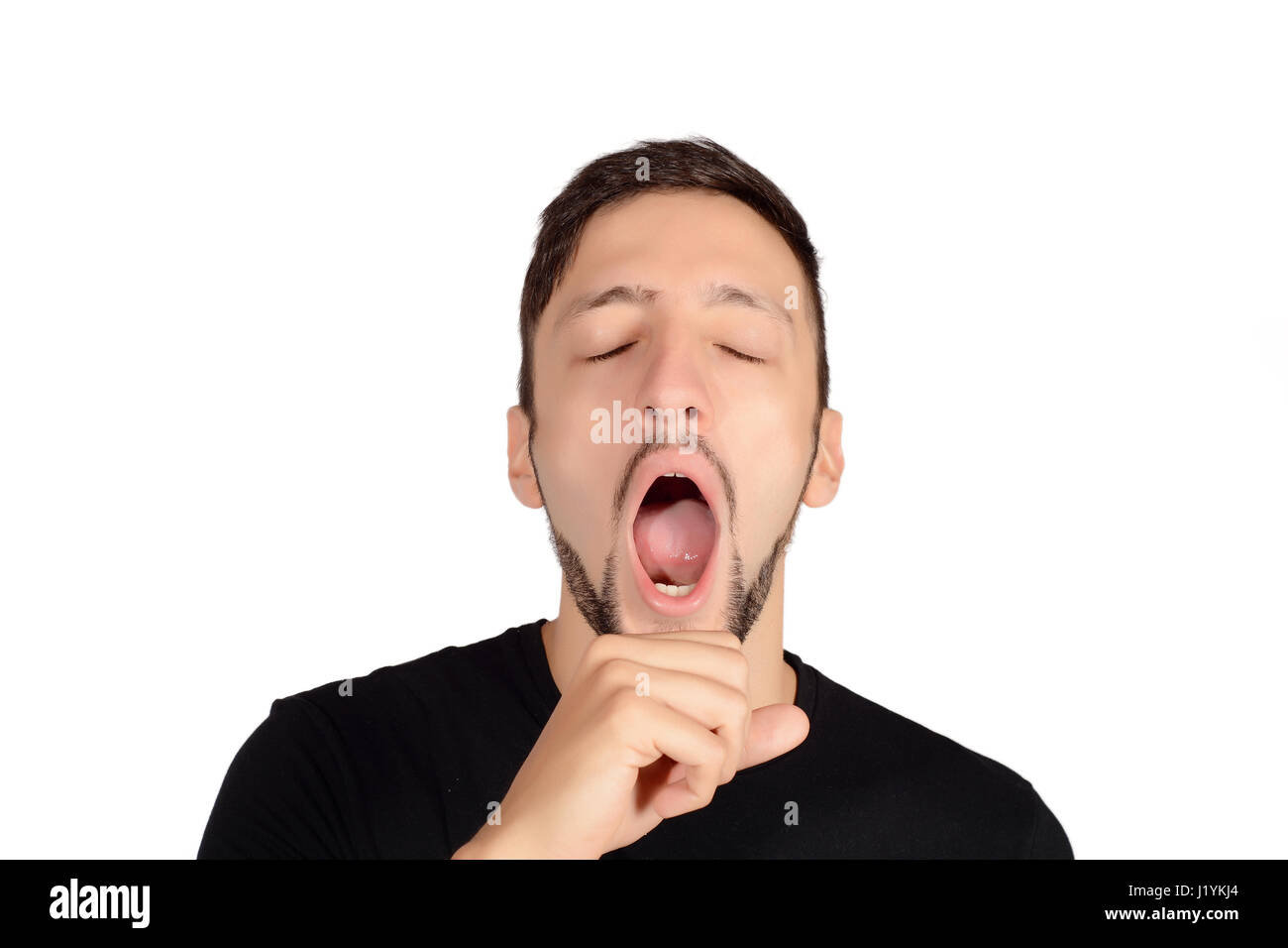 Portrait of a young man yawning. Isolated white background. Stock Photo