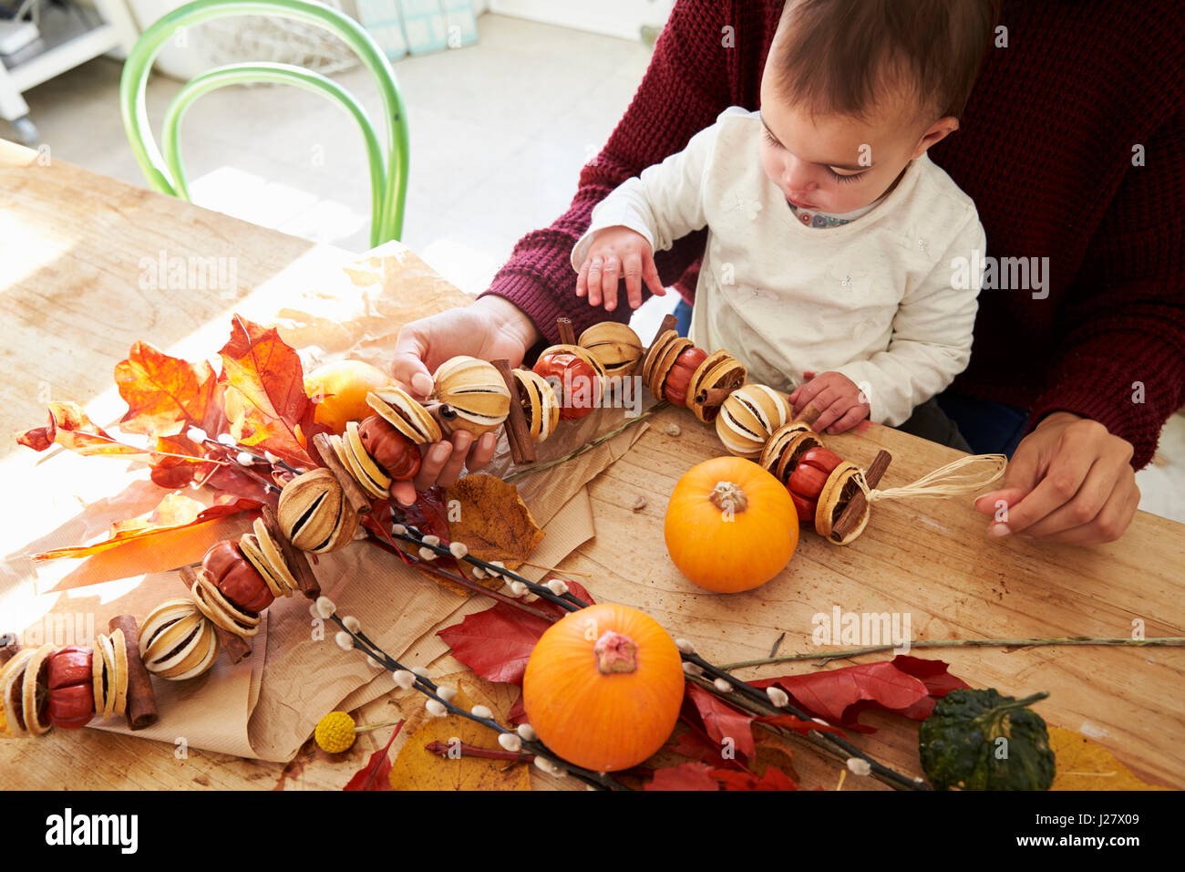 Mother And Daughter Making Autumn Decoration At Home Stock Photo