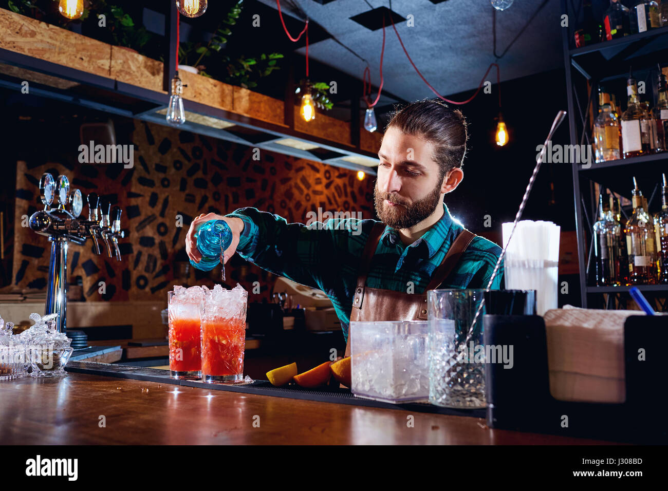 The barman with a beard makes  cocktail at  bar Stock Photo