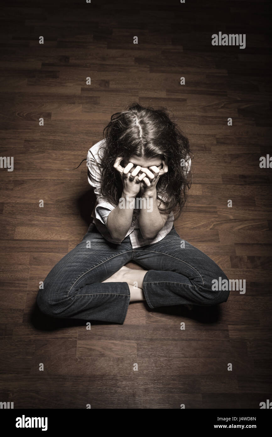 Sad woman sitting alone in a empty room Stock Photo