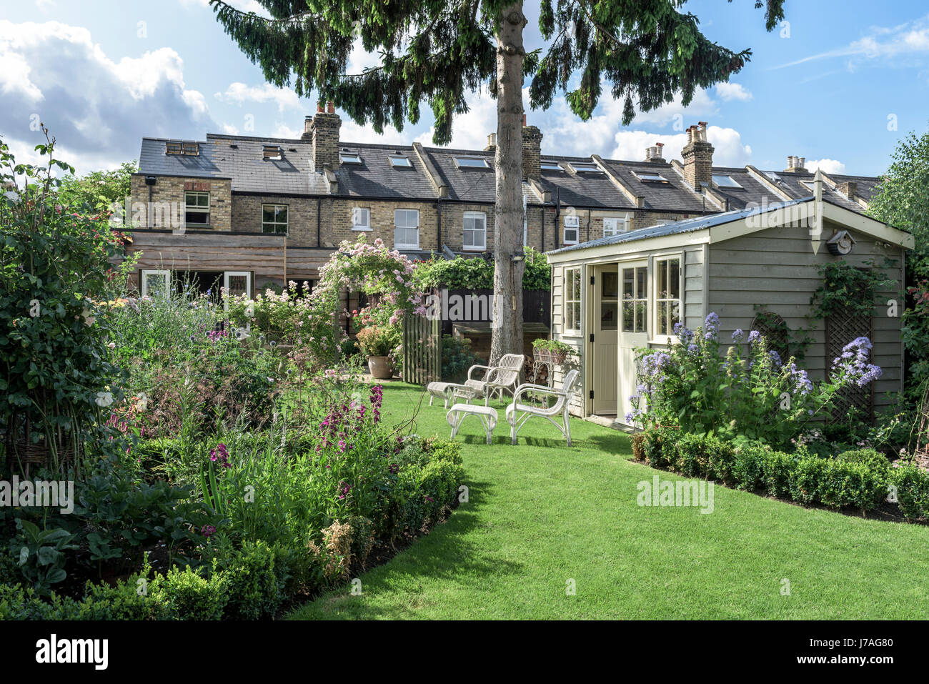 Summerhouse in english garden with wicker furniture and tidy lawns Stock Photo