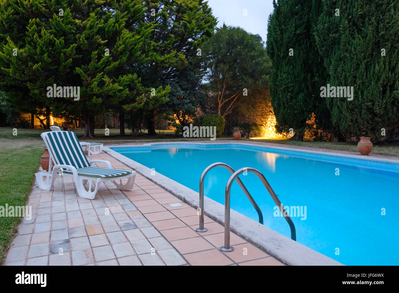 Deck chair next to outdoor swimming pool Stock Photo