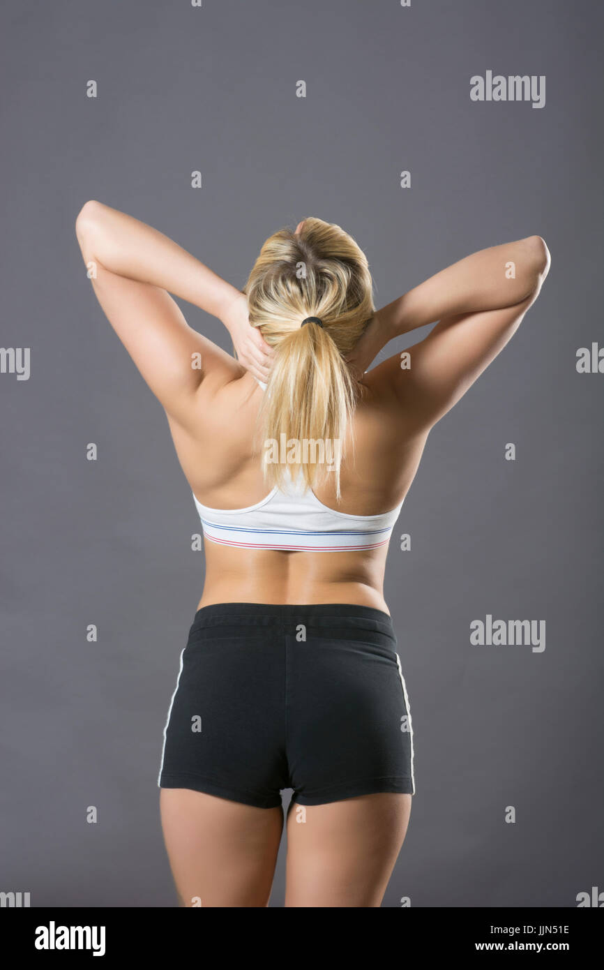 Rear view of a woman wearing sports bra and short hands on head Stock Photo